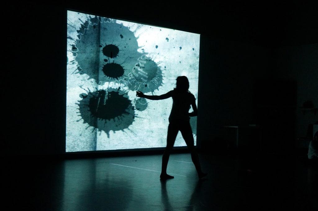 image of a person silhouetted against an image projected onto a wall