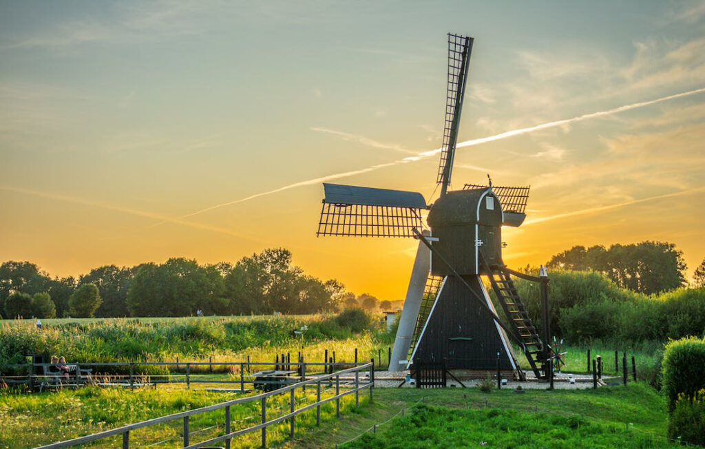 Black and White Wind Mill in Green Field Under Yellow Skies