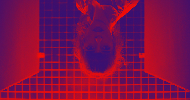 red tinted image of a woman looking down into the camera