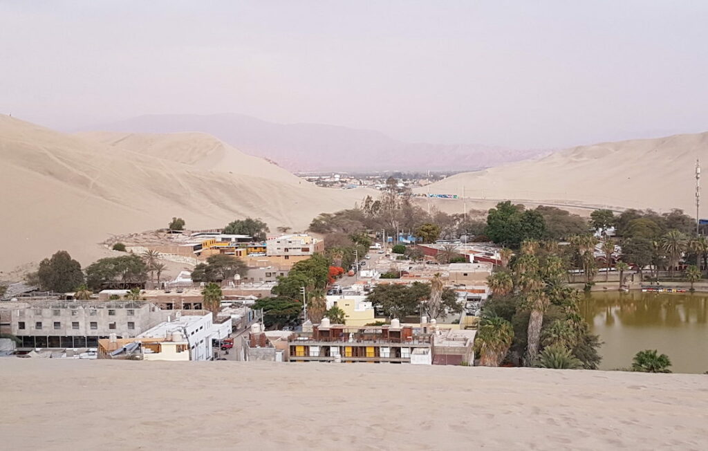 aerial view of a settlement nestled between sand dunes in a desert landscape