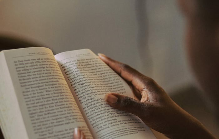 Closeup of a creative African man hands turning the pages of the book he is reading