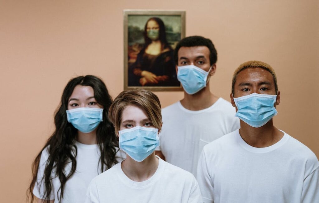 four masked patients stand in front of Da Vinci's Mona Lisa which is also masked