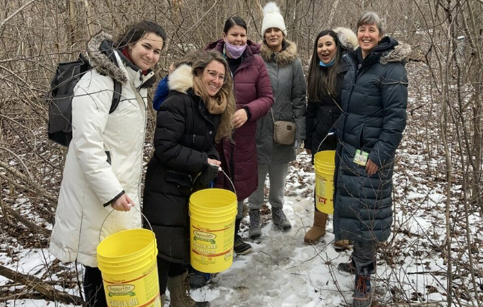 Photo of graduate students, professor, and members of the SweetGrass Roots Collective gathering sweet water at Black Creek Community Farm