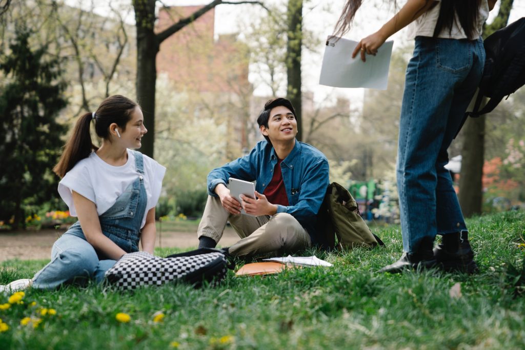An image of college students handing out in a park