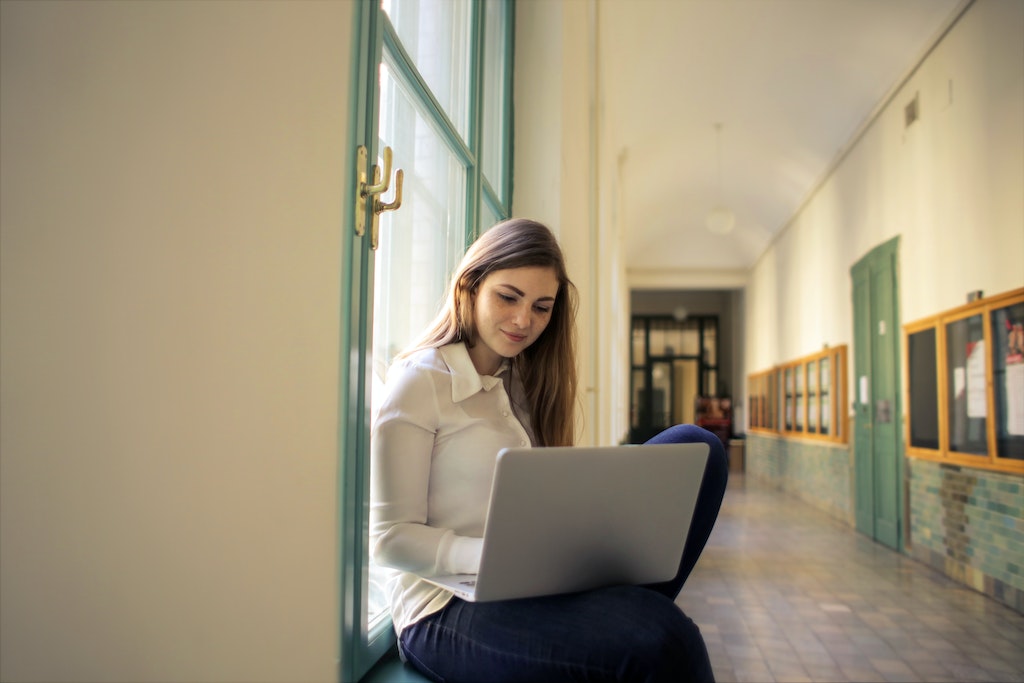 Photo of a woman in white shirt using laptop