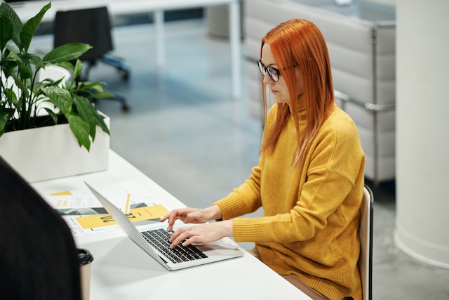 Woman in Yellow Sweater Using a Macbook