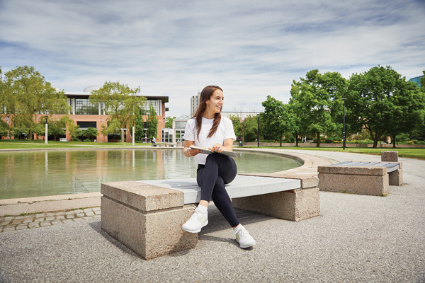 photo of a woman sitting on a stone bench beside the Commons reflecting pond