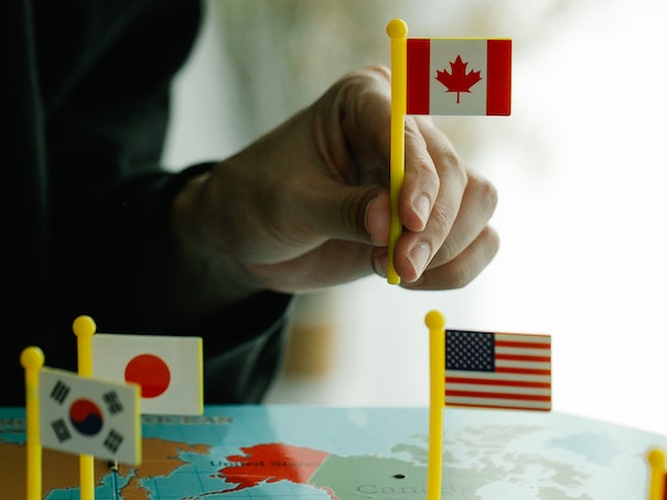 Hand of Person Placing Country Flag Markers on a World Map