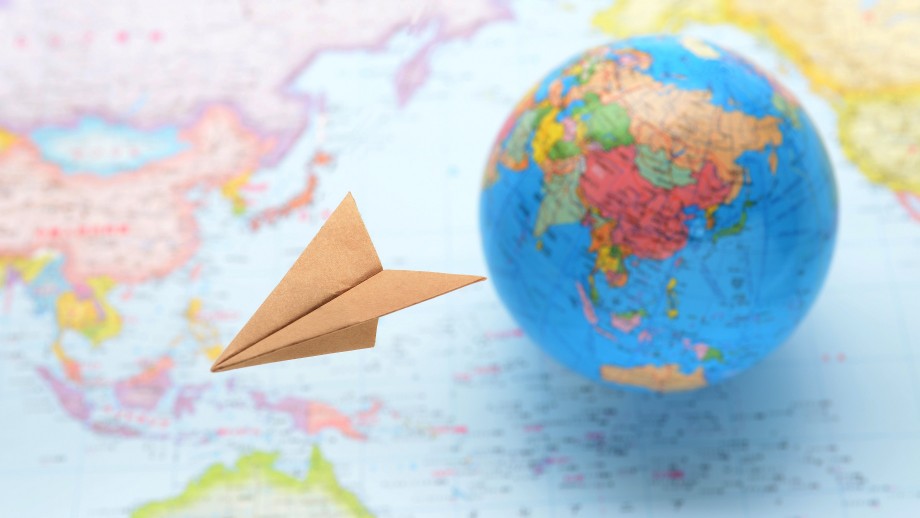 Paper plane and globe in the background on a map
