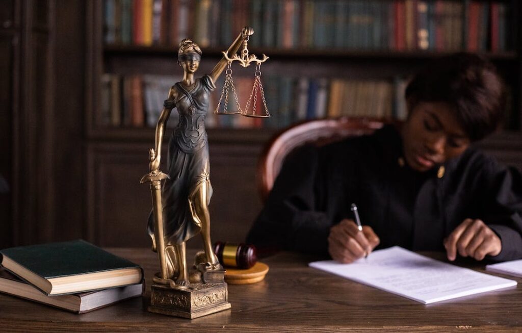 statue of Lady Justice on a desk top in front of a judge