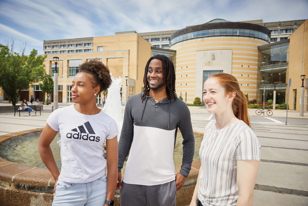 three students standing in front of the fountain at Vari Hall