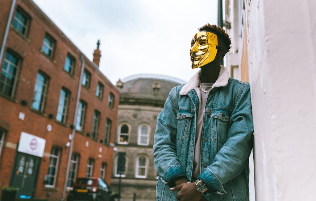 African American male wearing golden Anonymous mask as symbol of protest