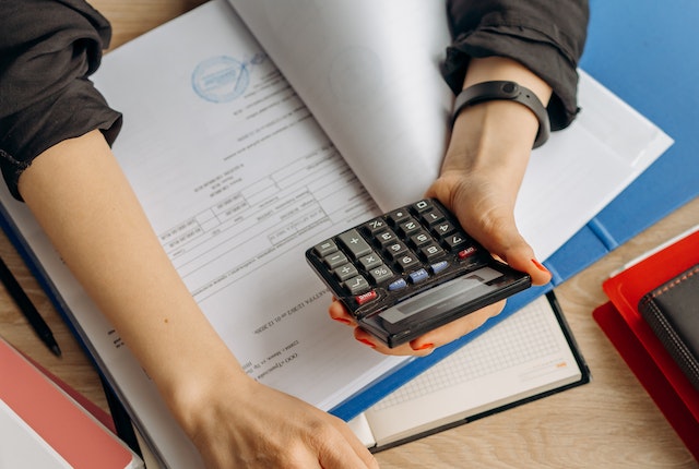 Person Holding Black Calculator While Using Laptop