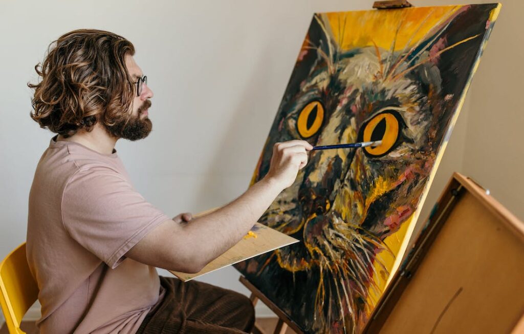 man in a t-shirt painting a portrait of a cat