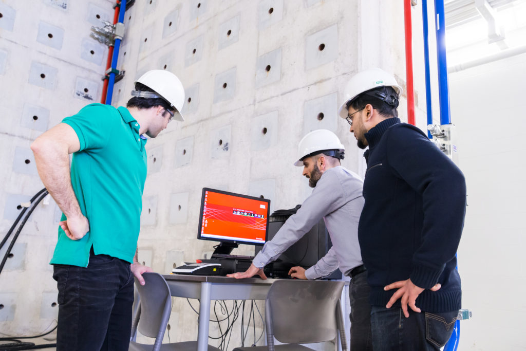 Image of three engineerings students standing around a computer