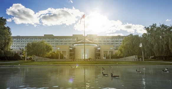 Image of Vari Hall with pond and a Canadian flag pole