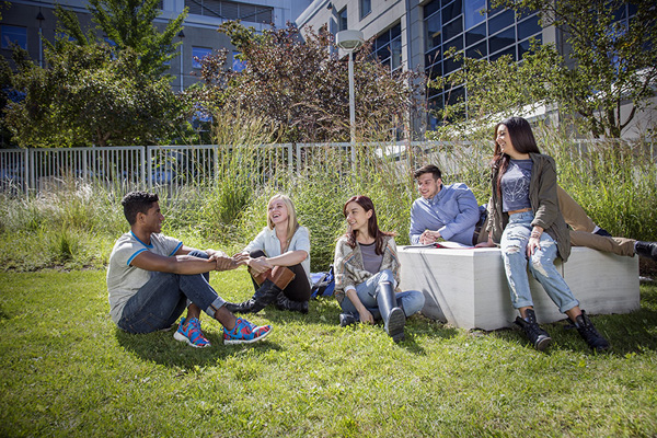 photo of a group of students sitting in a courtyard talking