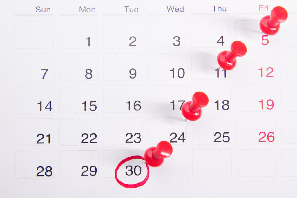 image of a calendar month with 30 circled and red pins placed in an assortment of dates