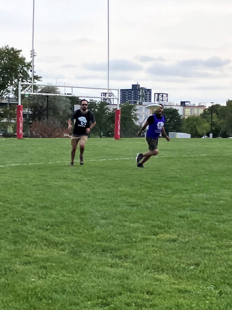 photo of two men playing frisbee on an outdoor field