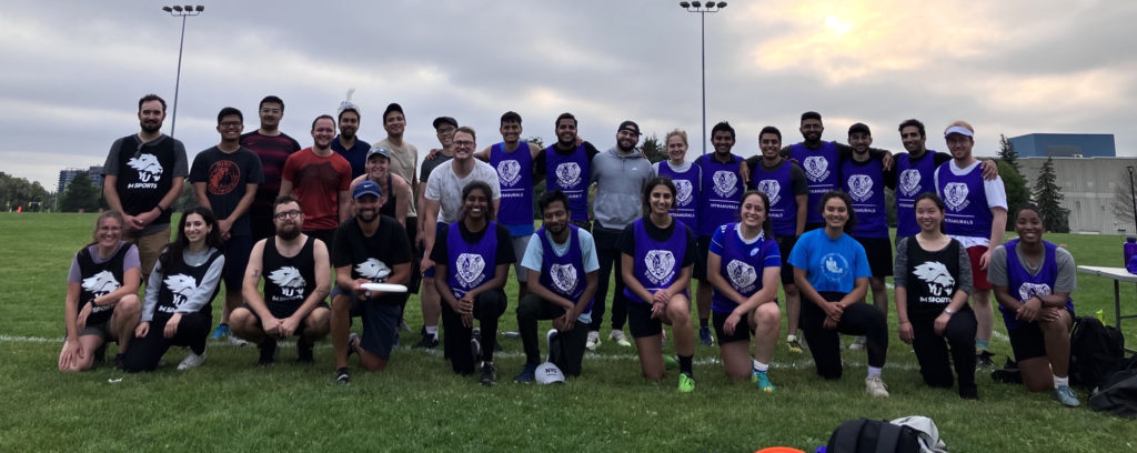 Grad Sports League participants pose for a group photo on an outdoor playing field