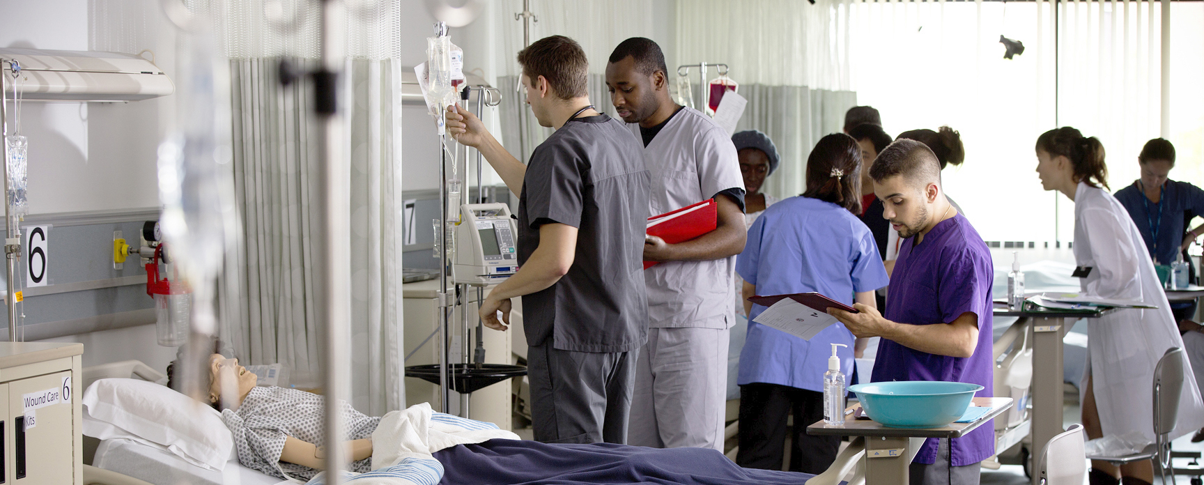Nursing students standing next to a Nursing simulation dummy in a hospital