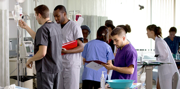 Nursing students standing next to a Nursing simulation dummy in a hospital