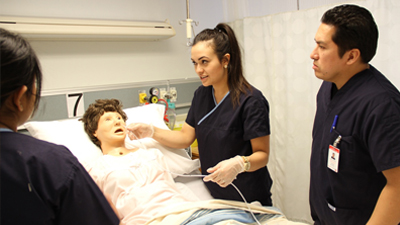 Nursing students practice on a nursing simulation dummy.