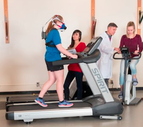 Researchers in a lab studying a Kinesiology student on a treadmill