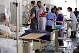 Nursing students standing by a hospital bed.