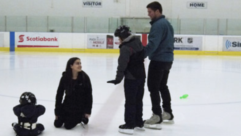 Two York University students helping young skaters on the ice.