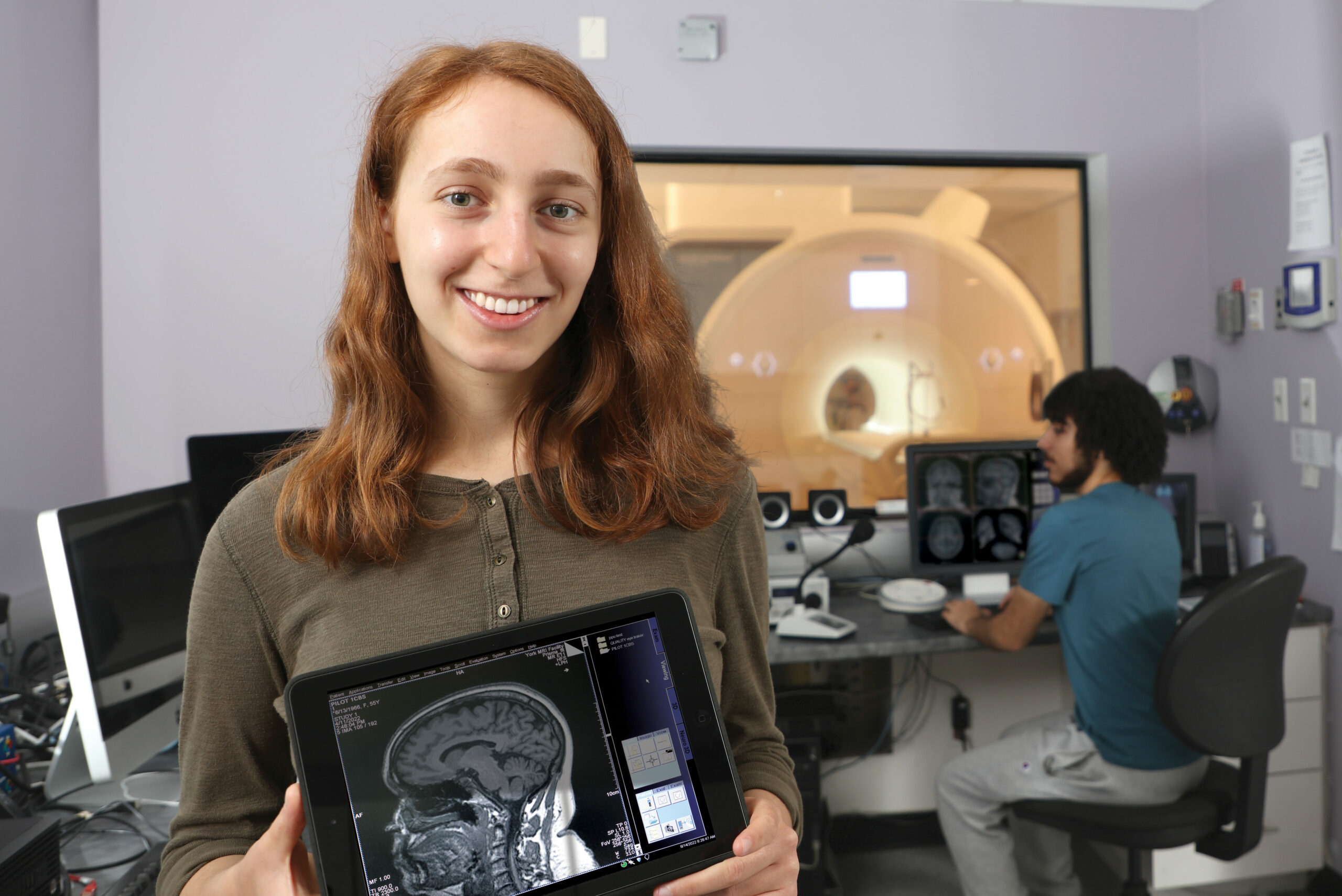 Student holding a tablet with an image of a brain on it