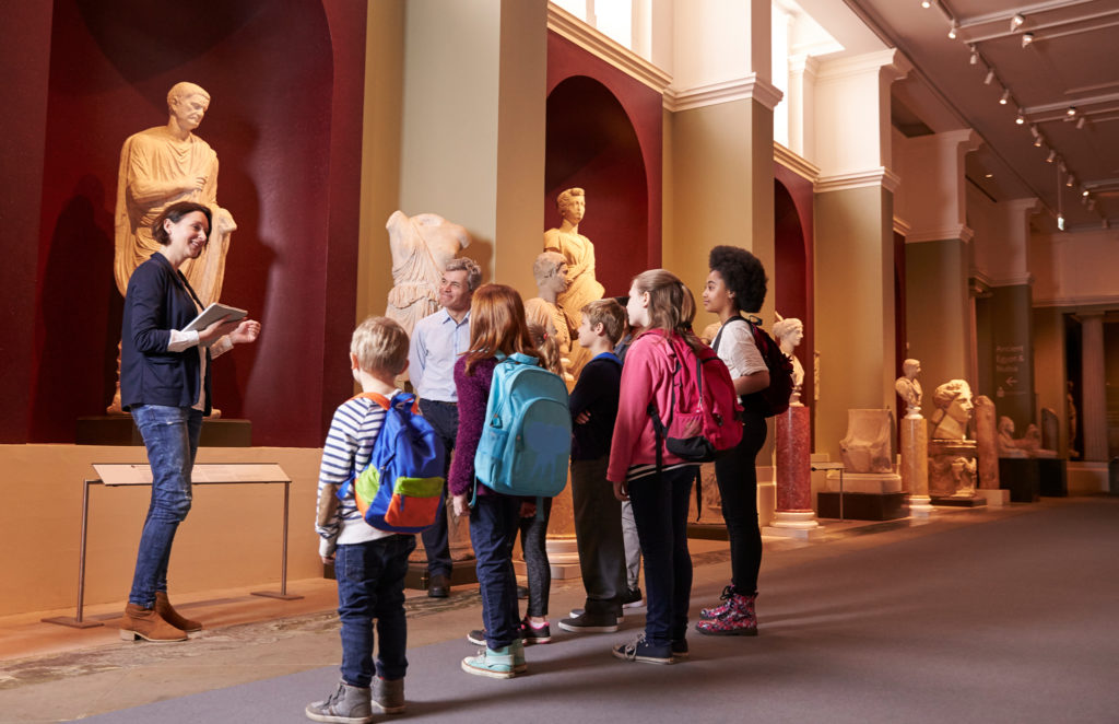 museum tour guide explaining ancient statue to kids