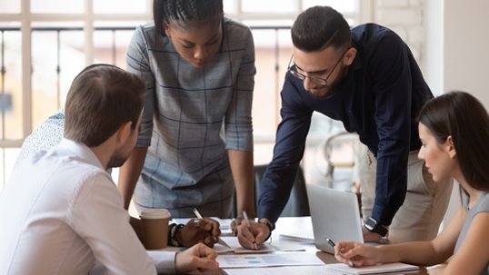 four young professional people meeting around table