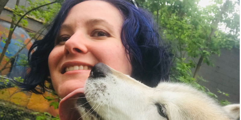 Niki Thorne smiling as a dog licks her chin playfully.