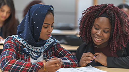 two women studying together in class