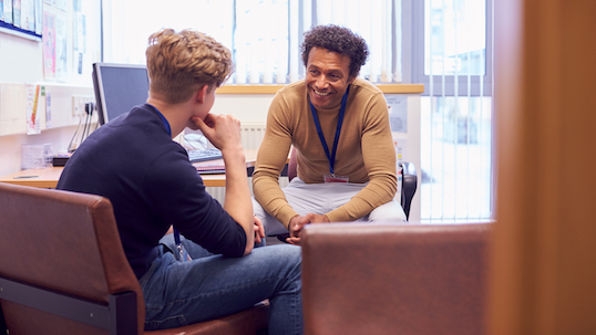 Male College Student Meeting With Campus Counsellor Discussing Mental Health Issues