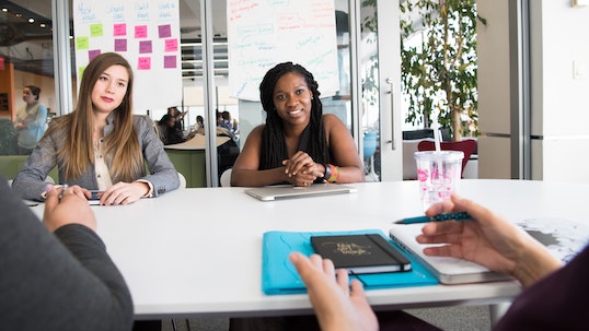two female students being interviewed in an office space