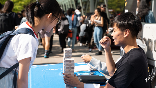 male student demonstrating a jenga game for a female student during a fair on keele campus