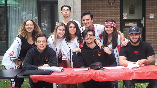 group of students pose for a photo around a table outdoors