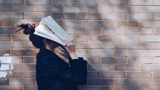 women with book on her face