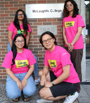 four college students in front of McLaughlin College sign