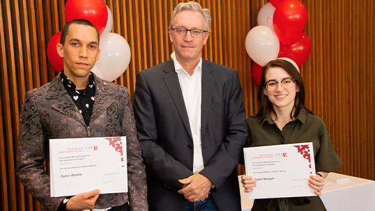 Students pose with professor while holding awards