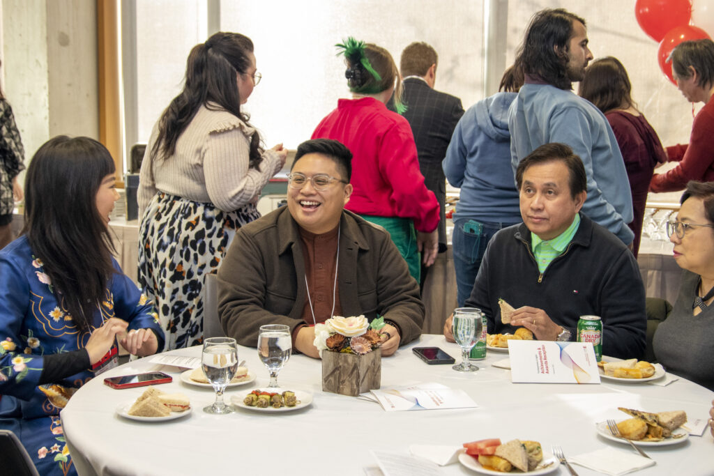 Candid photo of students and family at the reception, sitting at a table.