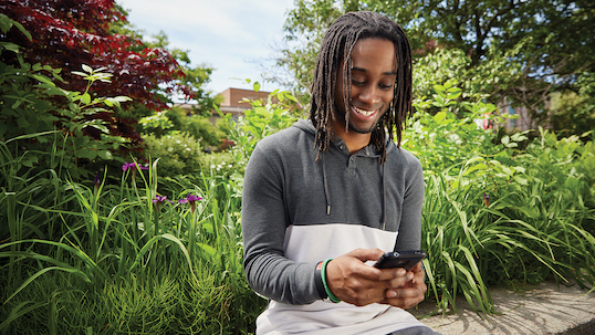 black man using mobile device in gardens