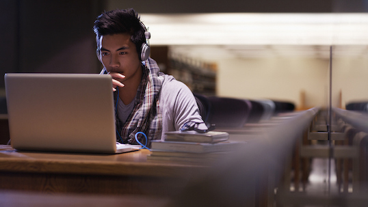 Young male student studies alone in library at night