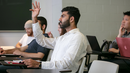 Man raises hand while seated in classroom