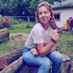 Dr. Andi Schwartz photo outside sitting on a wooden log and eating ice-cream