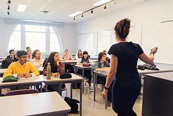 rear view of a woman addressing a class while the students sit and listen