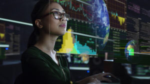 young Asian woman looking at see through global environmental data while seated in a dark office