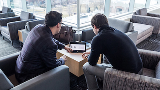 Two male students study together on tablet device